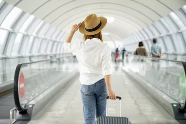 Young woman with rolling luggage in airport
