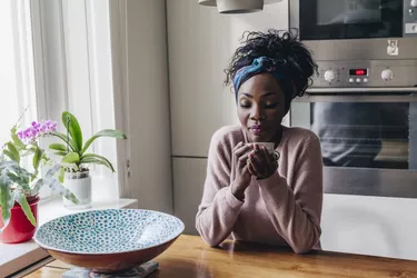 woman drinking coffee in her kitchen