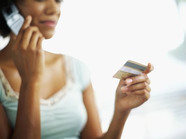 young woman talking on a mobile phone and holding a credit card