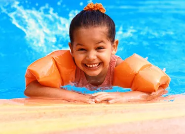 portrait of a young girl (3-5) wearing arm floats in a swimming pool