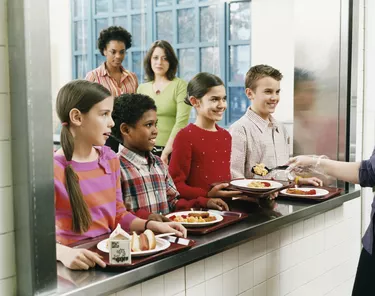 Four Schoolboys and Schoolgirls Looking at Person Serving Food on a Plate