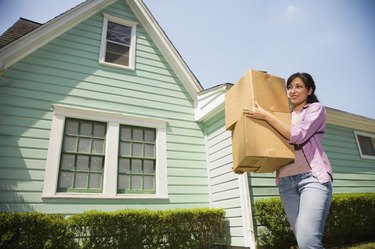 Hispanic woman carrying moving boxes outdoors