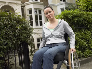 Woman sitting in wheelchair outside house, portrait