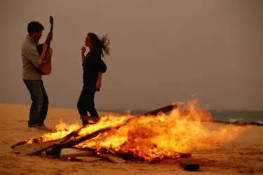 Young couple dancing by campfire at beach