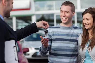 Couple receiving car keys by a dealer