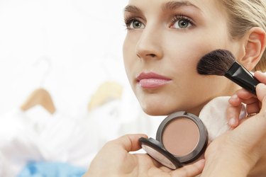 Using brush to apply blush on cheeks
