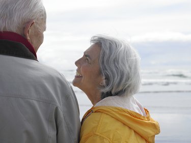 Senior couple embracing on beach, rear view