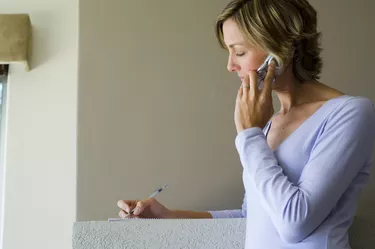 Woman talking on phone and writing