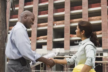 Architects shaking hands at construction site