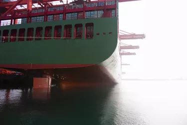 Stern of a green and red docked cargo ship.
