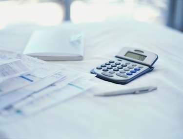close-up of bills with a calculator and a pen