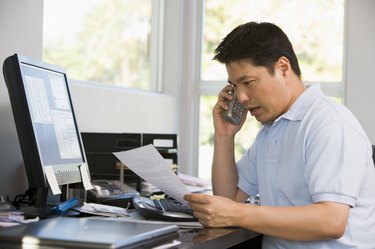 Man in home office with computer and paperwork on