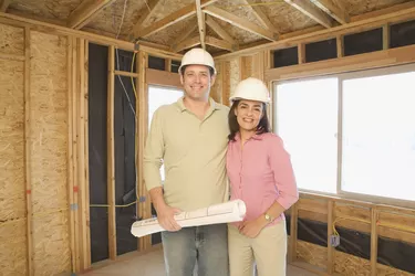 Couple in hard hats with blueprints on construction site