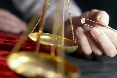 Person weighing gold pieces