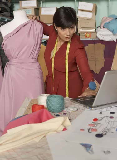 Female fashion designer using laptop in studio