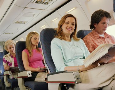 Woman relaxing on plane, smiling, portrait