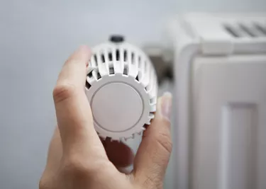 Woman Adjusting The Thermostat