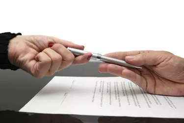businessman giving pen to businesswoman for signing contract or document