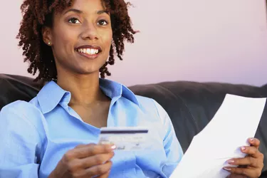Close-up of a young woman holding a credit card and a bill