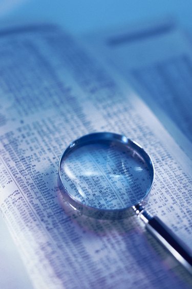 Magnifying glass on financial page of newspaper