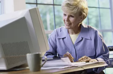 Senior woman sitting in front of a computer monitor