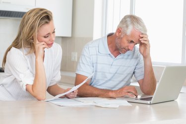 Worried couple working out their finances with laptop