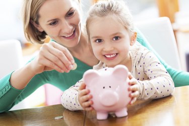 Mother and daughter playing with piggy bank