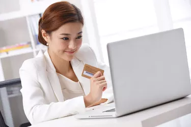 Young business lady holding credit card in front of laptop