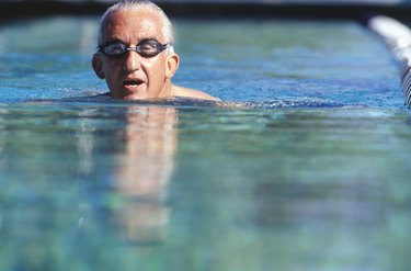 Senior man swimming in outdoor pool, surface view