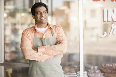 Shopkeeper smiling by storefront