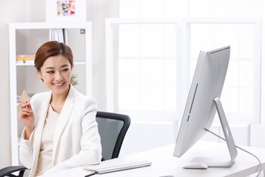 Young business lady holding credit card in front of computer