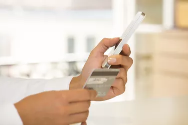 Woman's hands holding credit card and using cell phone