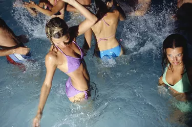 Medium group of young adults dancing in pool at night, elevated view, waist up