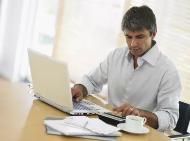 Man using laptop and calculator at desk