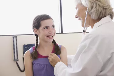 Doctor examining teenage girl with stethoscope