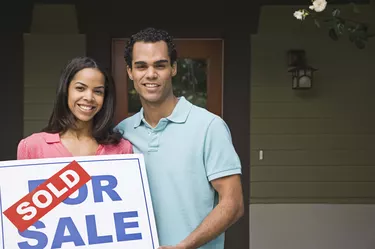 Couple with house and sold sign