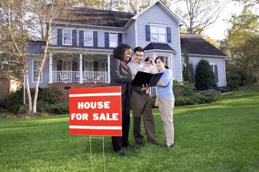 Family with real estate agent outside house