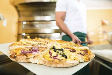 Man pushing the finished pizza from oven