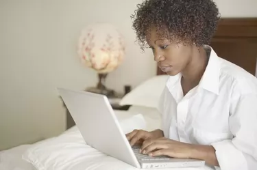 Woman sitting in bed with laptop