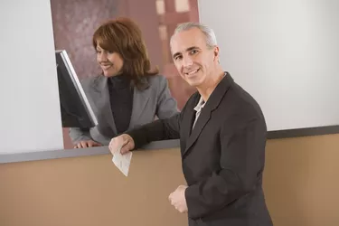 Man waiting at counter while receptionist checks monitor