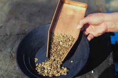 Person pouring gold nuggets into a pan