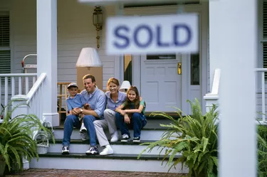 Portrait of parents sitting on the stairs of a house with their son and daughter