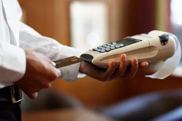 Young man sliding credit card into portable swipe machine, close-up