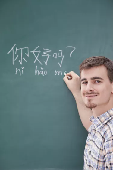 Portrait of smiling male teacher in front of chalkboard writing