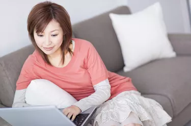 Woman typing on laptop and sitting on sofa