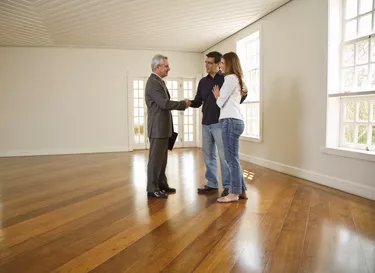 Couple shaking hands with realtor in empty room