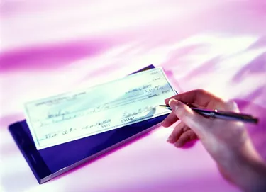 high angle view of a woman's hand writing a cheque