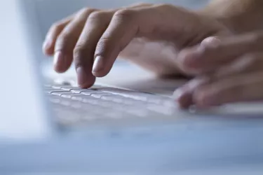 Hands typing on laptop computer, close-up