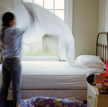 Girl (10-12) making bed, rear view (blurred motion)