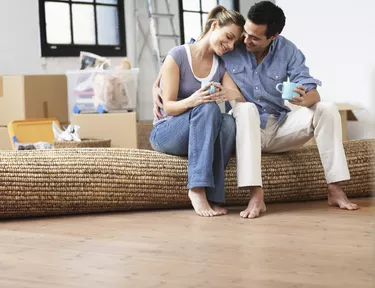 Couple embracing, sitting on mat indoors, smiling